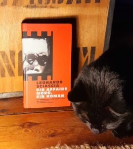 Buchcover "Die Affaire Moro" fotografiert vor einer Teekiste mit einer schwarzen Katze im Vordergrund